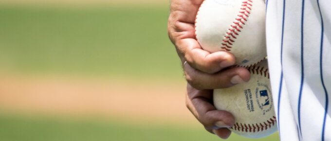 A man holding two white baseballs.